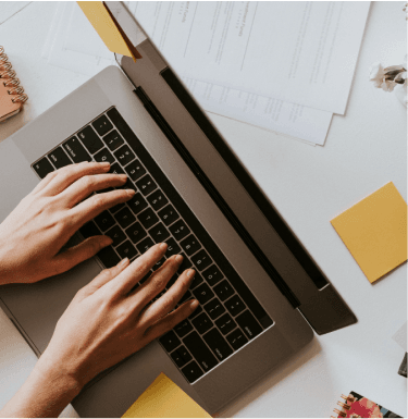 Professional reviewing documents at a desk with a laptop